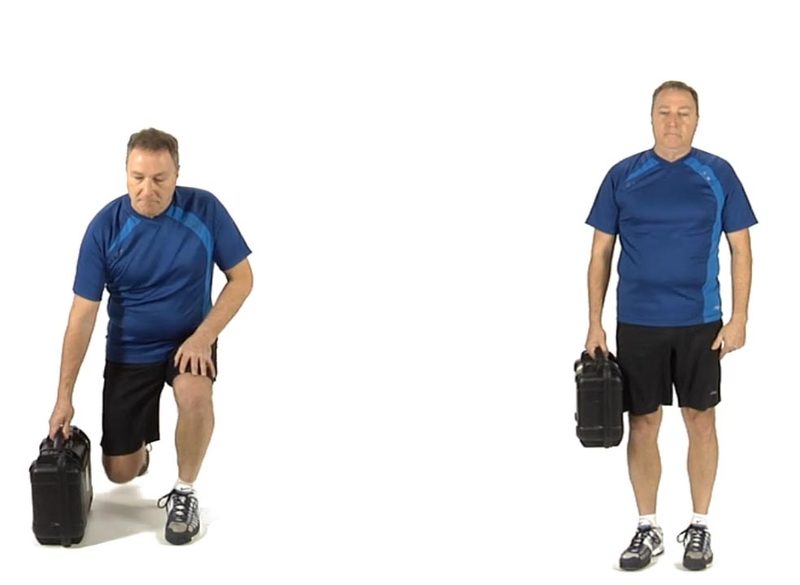 Un homme plus âgé en t-shirt bleu et short noir soulève une valise noire en utilisant une technique sécuritaire. À gauche, il est en position de fente au sol : un genou (gauche) posé au sol, l’autre jambe (droite) fléchie devant lui, pied à plat, tout en saisissant la valise d'une main. À droite, il est debout, tenant la valise le long du corps avec le bras droit, le dos droit et les jambes alignées.